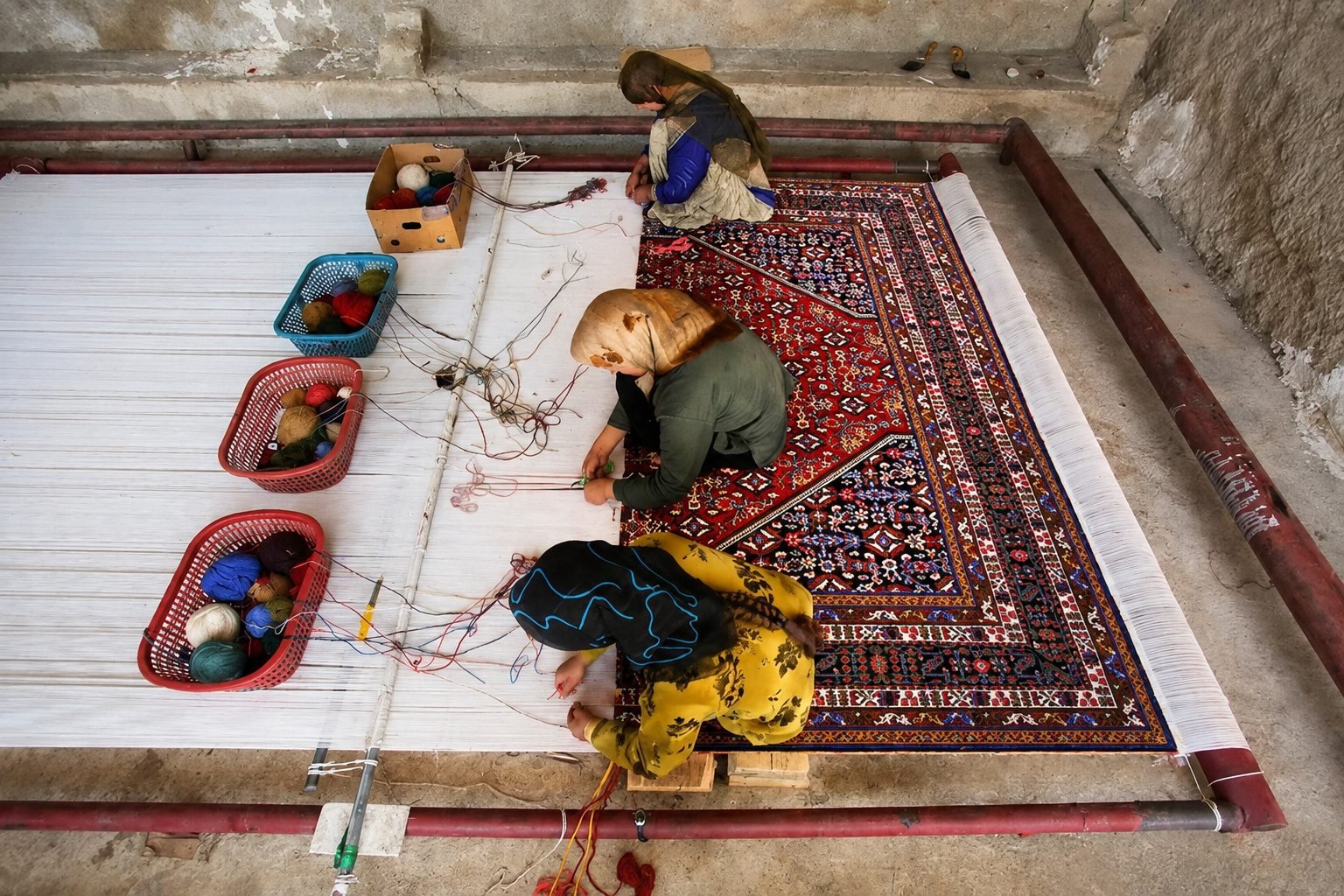 Artisans hand-knotting a vibrant Persian rug on a floor loom